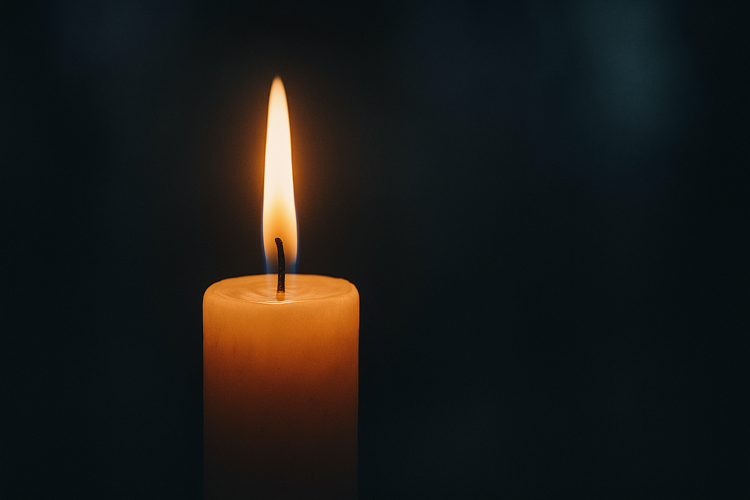 Vela acesa em um ambiente escuro, com chama dourada brilhando suavemente. O fundo está desfocado, criando uma atmosfera serena e introspectiva.